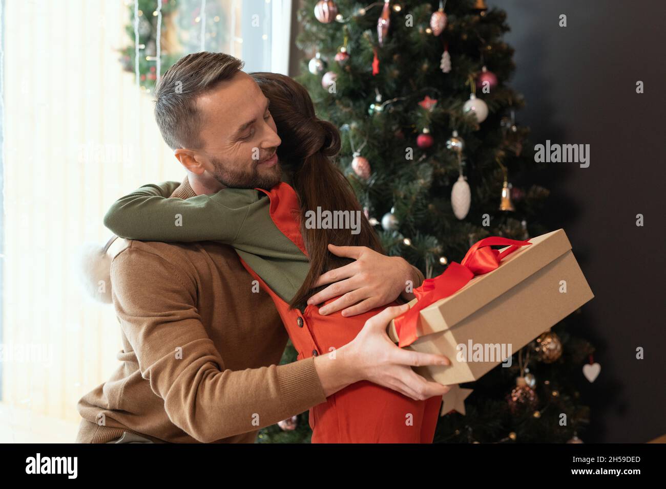Liebevolle kaukasische bärtige Vater in Pullover kuscheln Tochter, während ihr frohe Weihnachten Stockfoto