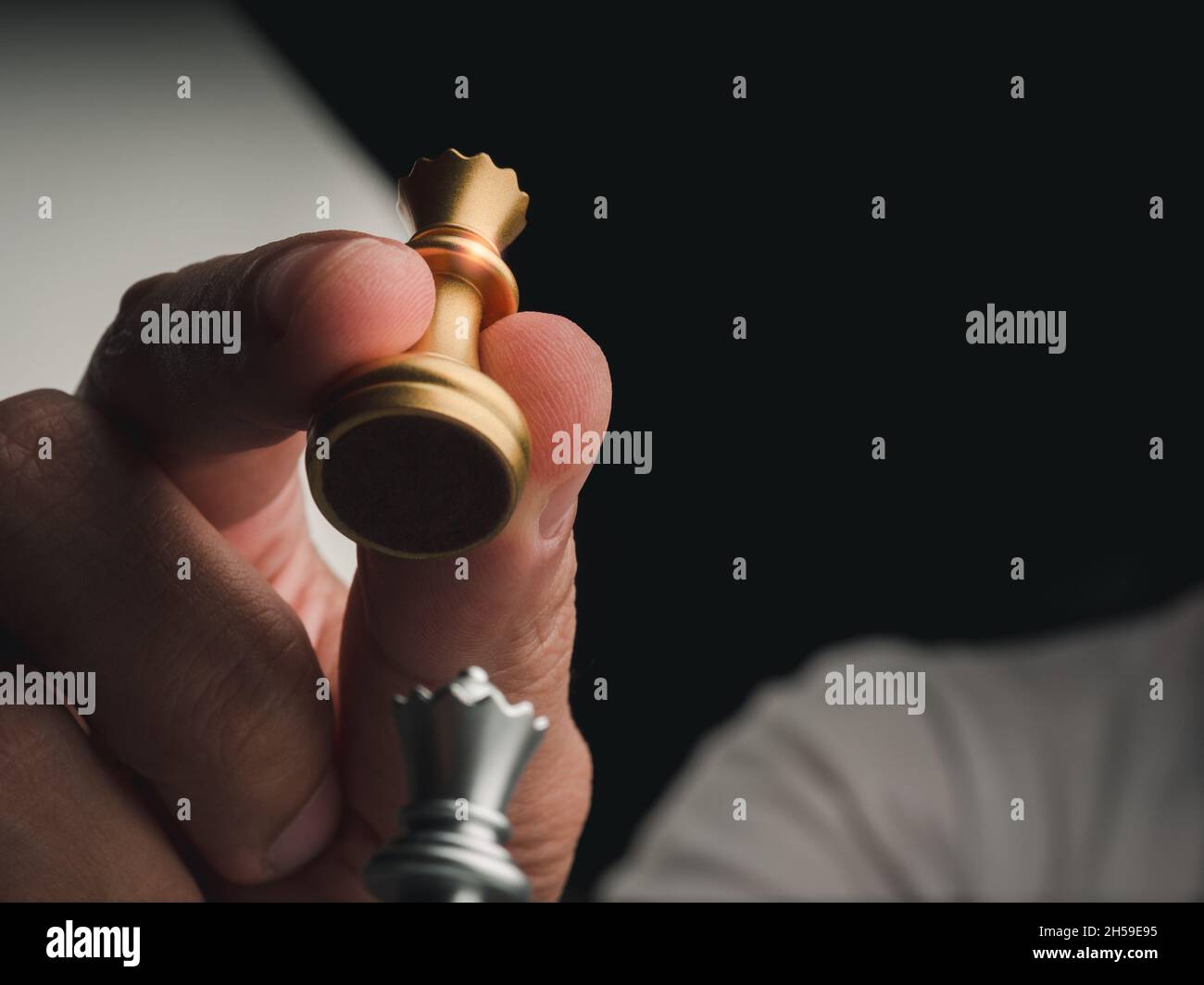 Nahaufnahme des Schachspiels der goldenen Königin in menschlicher Hand mit Kopierraum. Handbewegende Schachfigur der Königin, die bereit ist, die silberne Königin beim Schachspiel anzugreifen Stockfoto