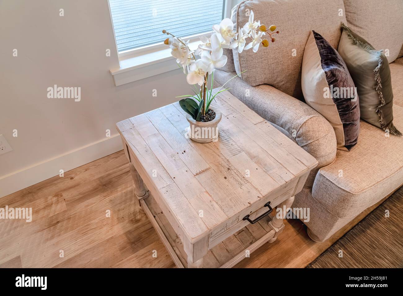 Beistelltisch mit Blume neben dem Sofa am Holzfußboden und Teppich des  Wohnzimmers Stockfotografie - Alamy