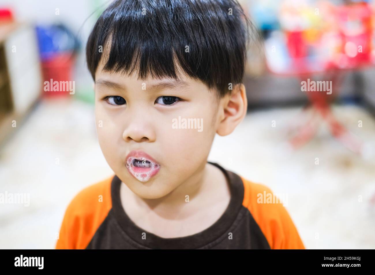Ein kleines Kind genießt den Schaum des Speichels, der aus seinem Mund spuckt. Stockfoto
