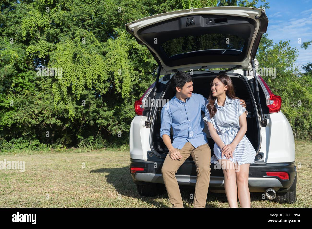 Glückliches junges Paar sitzt im offenen Auto zurück Stockfoto