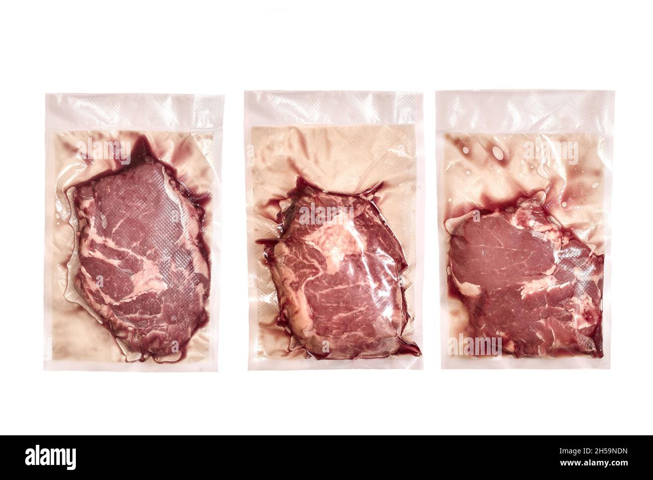 Ungeöffnete Packung mit drei rohe Rindersteaks auf weißem Hintergrund. Stockfoto