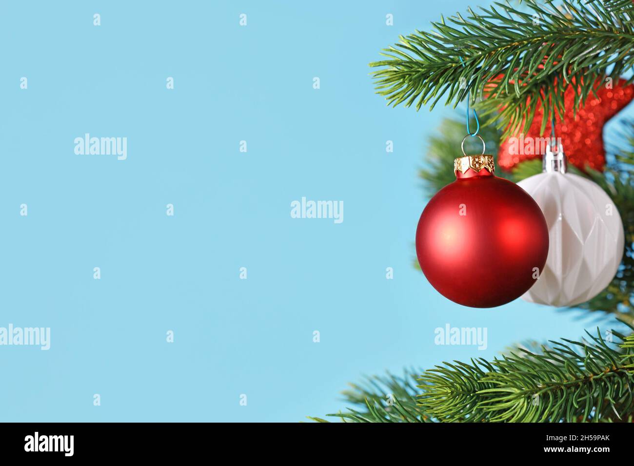 Kugelförmige rote Weihnachtskugeln auf Weihnachtsbaum auf der Seite des blauen Hintergrunds mit Kopierraum Stockfoto