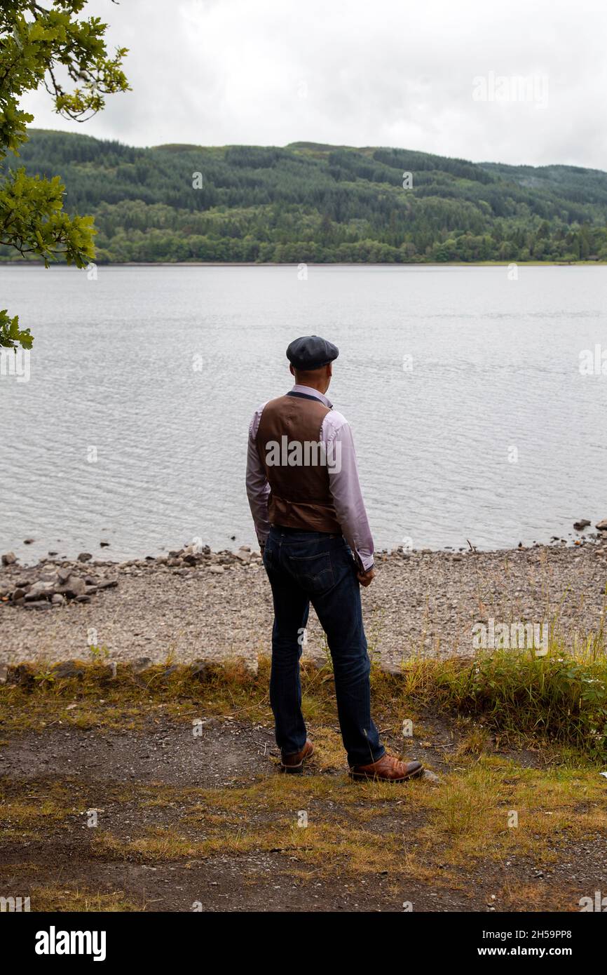 Mann in Weste und Jeans, der am See steht Stockfoto