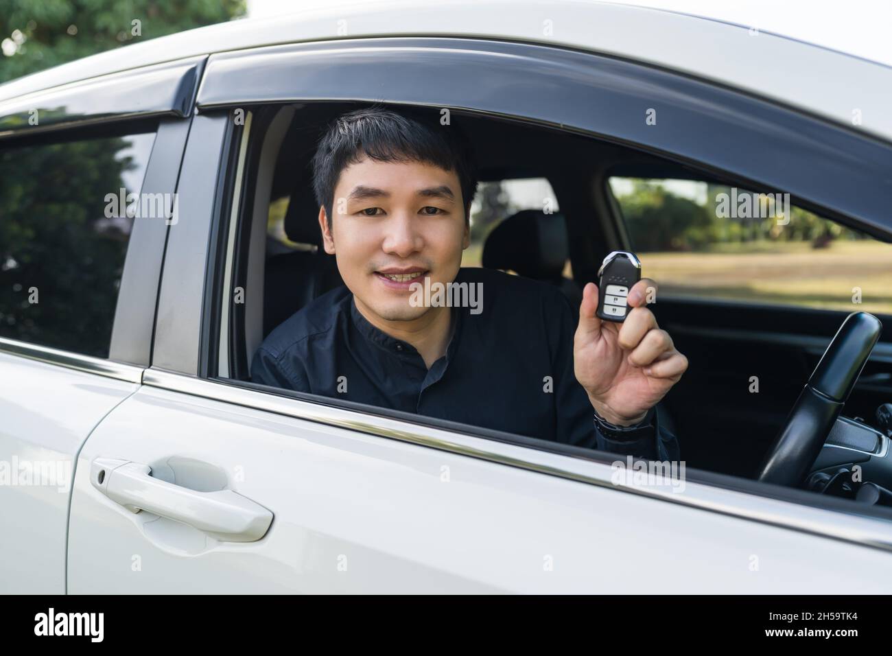 Junger Mann mit intelligenter Schlüsselfernbedienung in einem Auto Stockfoto