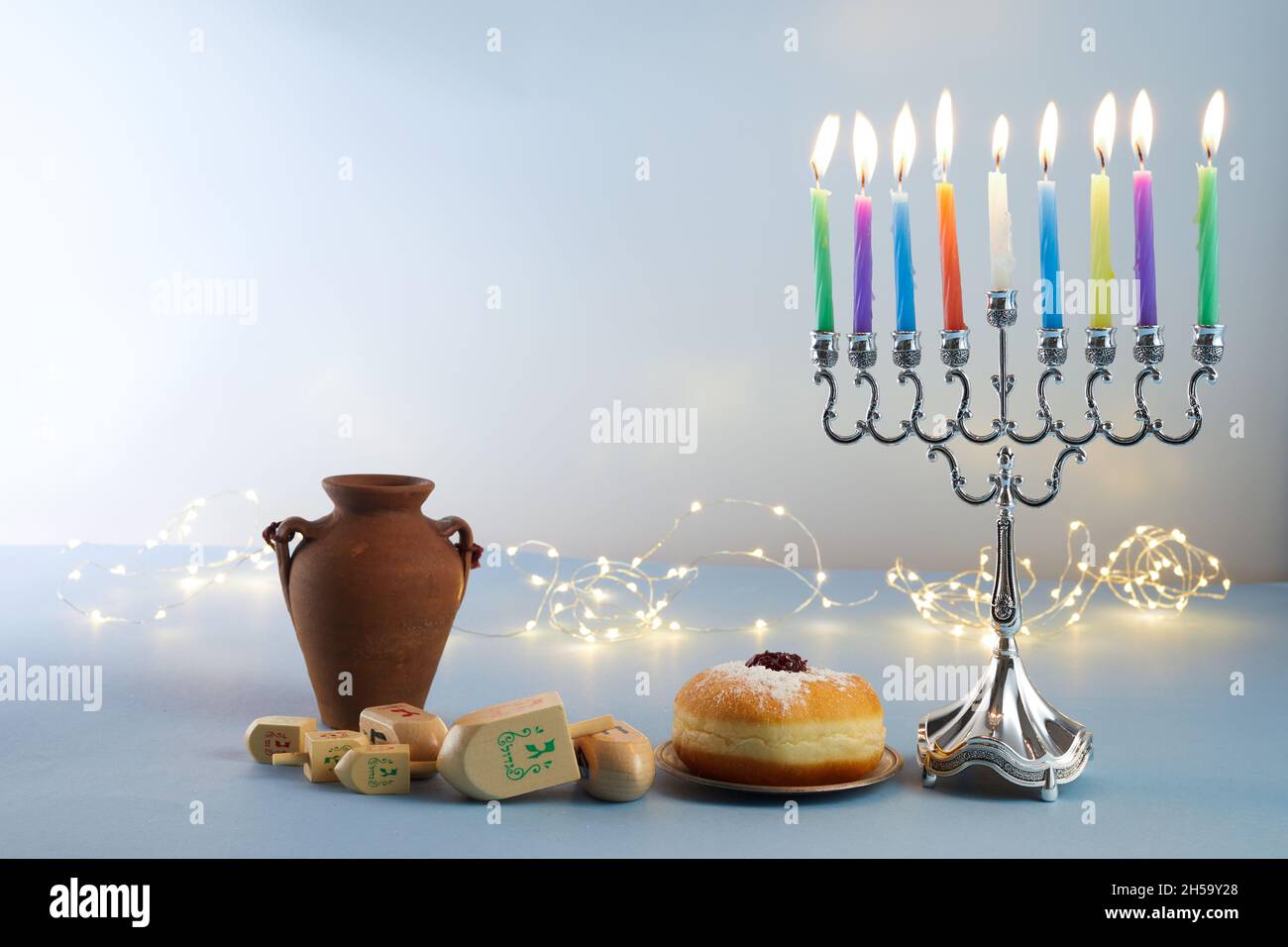 Jüdischer Feiertag Chanukka Hintergrund mit Menora- traditionelle Kerzenleuchter, Kreisel und Donut auf blauem Hintergrund Stockfoto