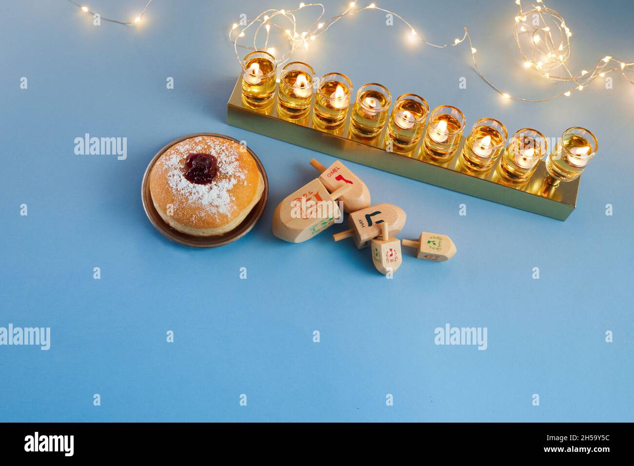 Jüdischer Feiertag Chanukka Hintergrund mit Menora- traditionelle Kerzenleuchter, Kreisel und Donut auf blauem Hintergrund Stockfoto