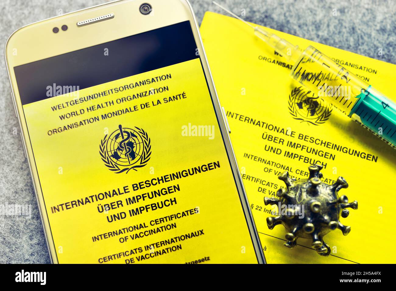 Impfpass, Impfspritze, Coronavirus-Modell und Smartphone, digitaler