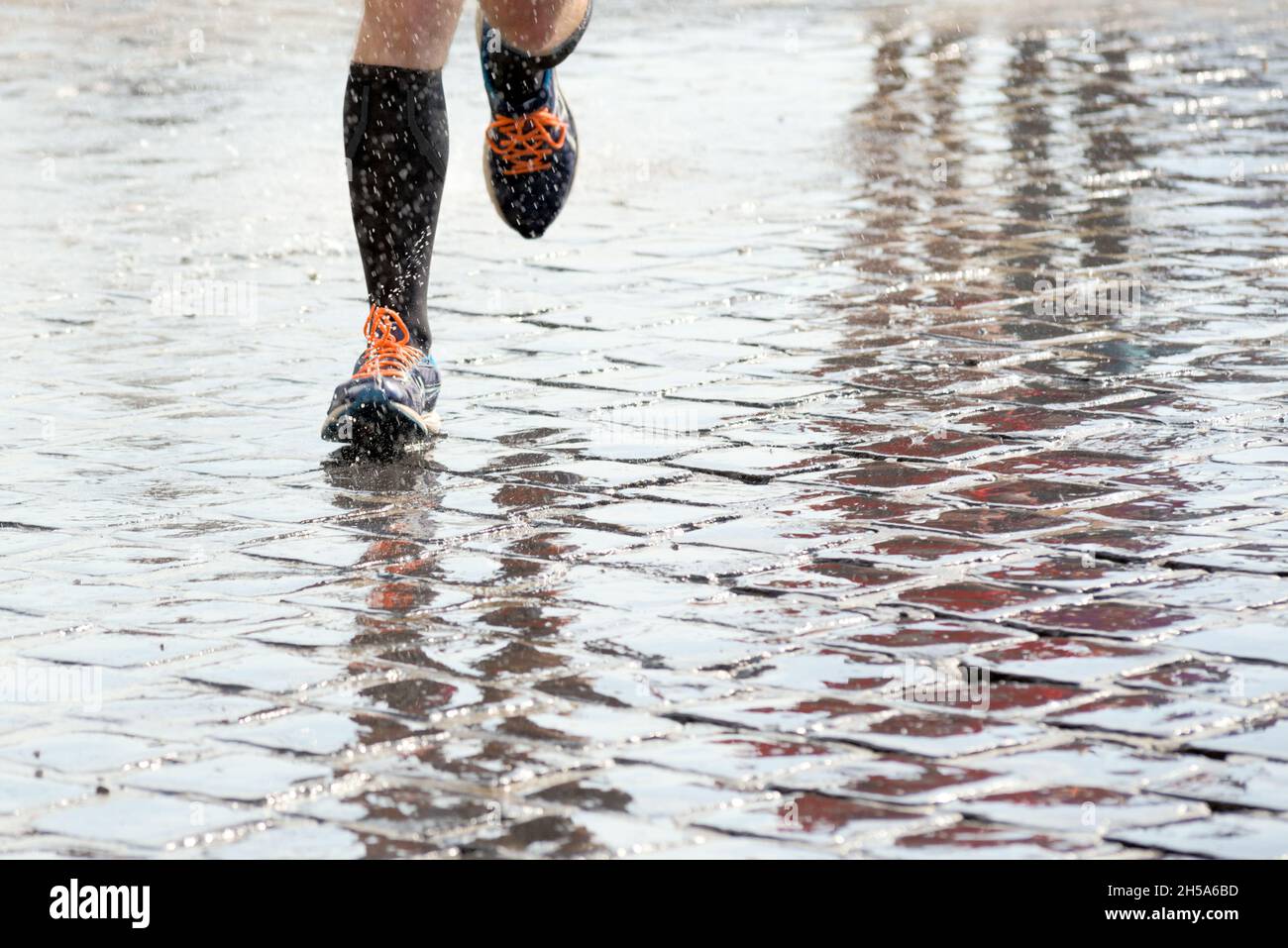 Füße einer Person, die im Regen draußen läuft Stockfoto