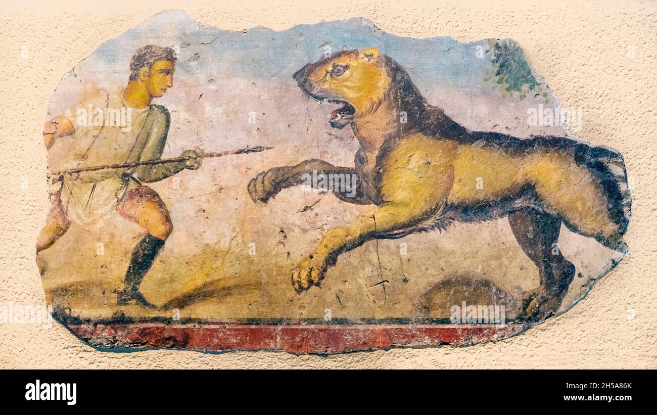 Detail eines römischen Wandbildes. Ein Jäger konfrontiert einen aufladerlichen Löwen. Das Gemälde kann auch einen Venator (das lateinische für Jäger) darstellen, der dem Tier gegenübersteht Stockfoto