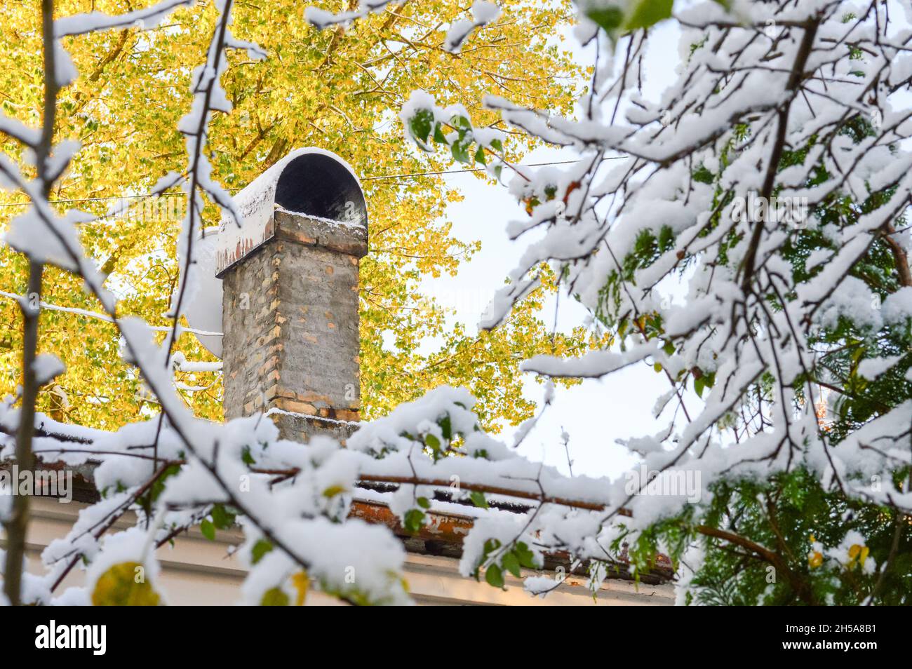 Ein Ziegelkamin für die Ofenheizung auf dem Dach eines Hauses. Holzheizung, Beginn der Heizperiode bei kaltem Wetter. Stockfoto