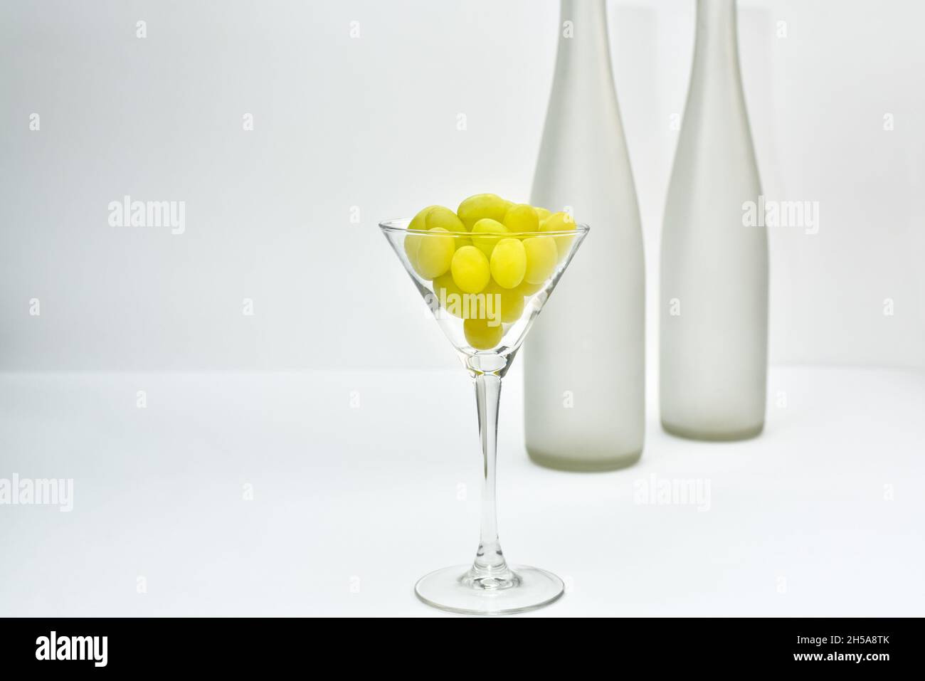 Weinglas mit Trauben auf dem Hintergrund einer verschwommenen leeren Weinflasche. Weinproduktion und Weinherstellung Thema Stockfoto