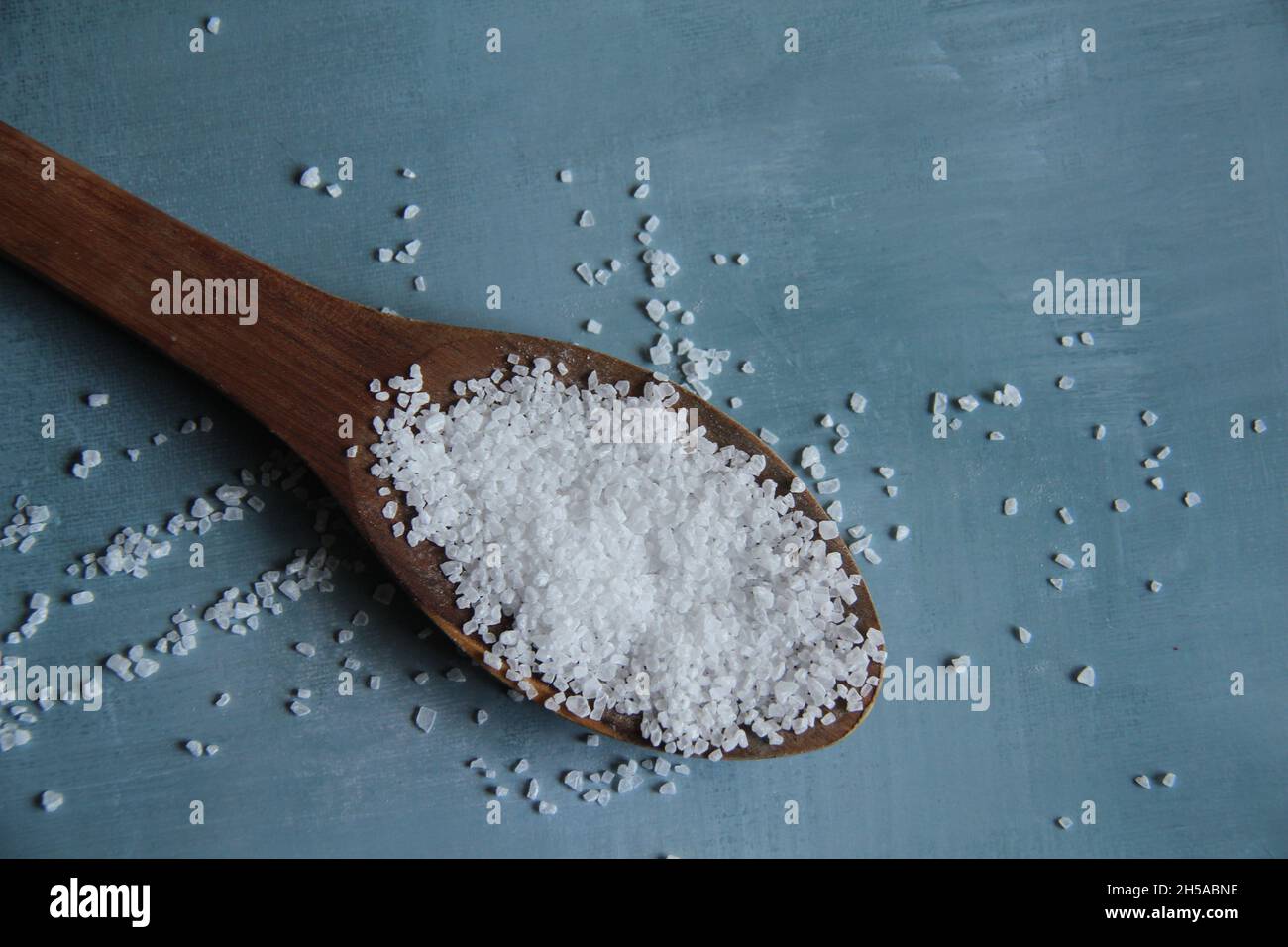 Grobes Salz, in einem Holzlöffel, auf einem alten Holztisch. Blick von oben. Stockfoto