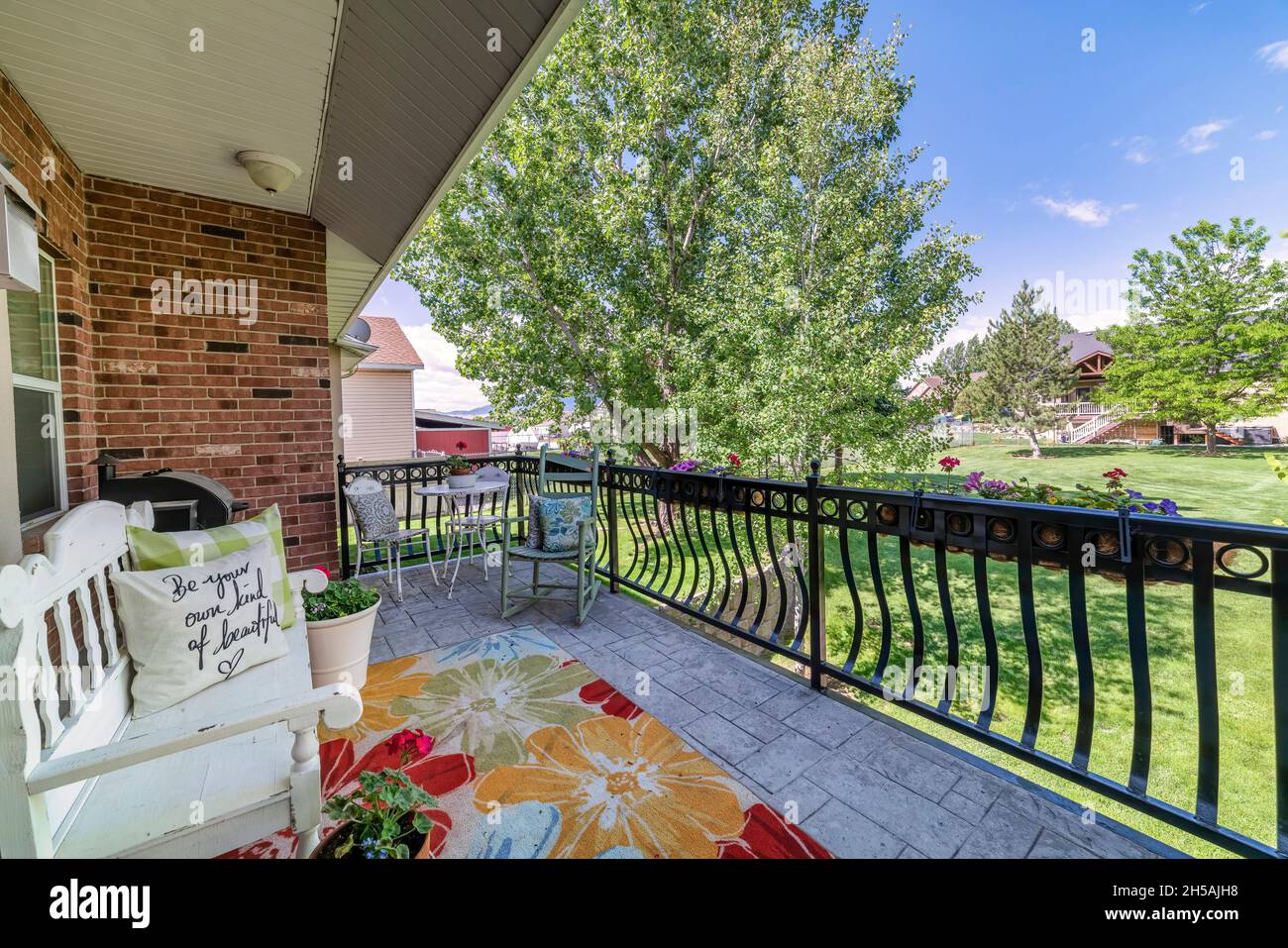 Terrasse im Freien auf einer Terrasse mit Blick auf ein großes grünes Feld mit Bäumen und Nachbarschaft Stockfoto