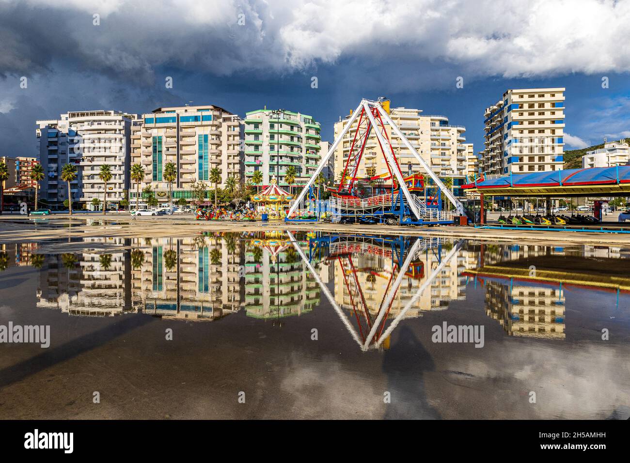 Hochhäuser und Jahrmarkt von Vlora Albanien spiegeln sich im Regenwasser wider, wenn sich ein weiterer Sturm nähert Stockfoto