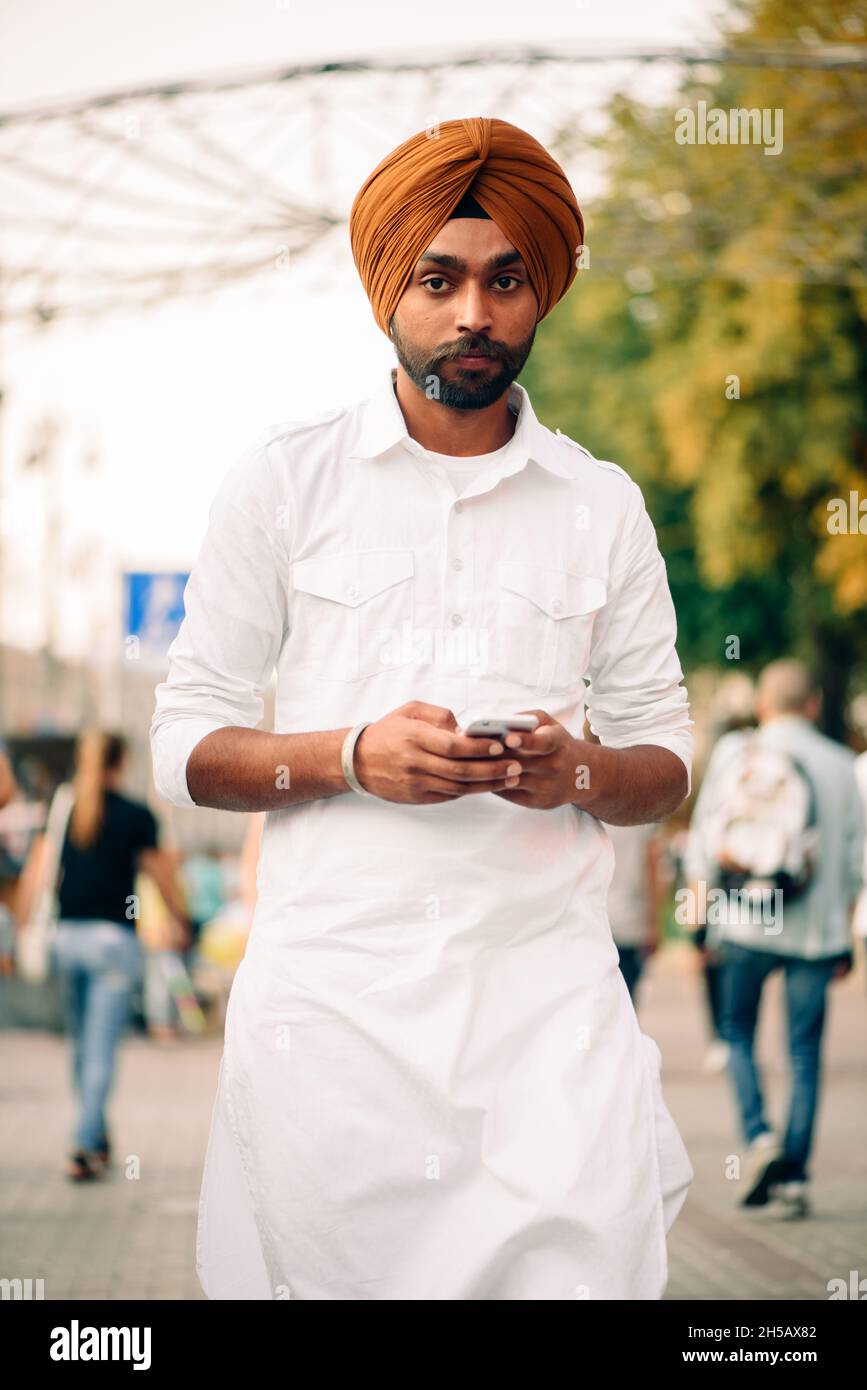 Kiew, Ukraine - 23. August 2021. Khreshchatyk St. Porträt eines indischen jungen erwachsenen Mannes in Turban gekleidet weißen traditionellen Kleidung Blick auf die Kamera Stockfoto