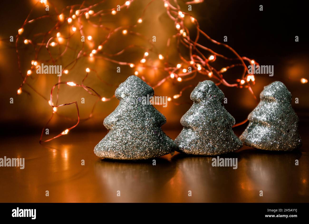 Drei weihnachtsspielzeuge, die auf einem goldenen Hintergrund mit Lichtern leuchten. Stockfoto