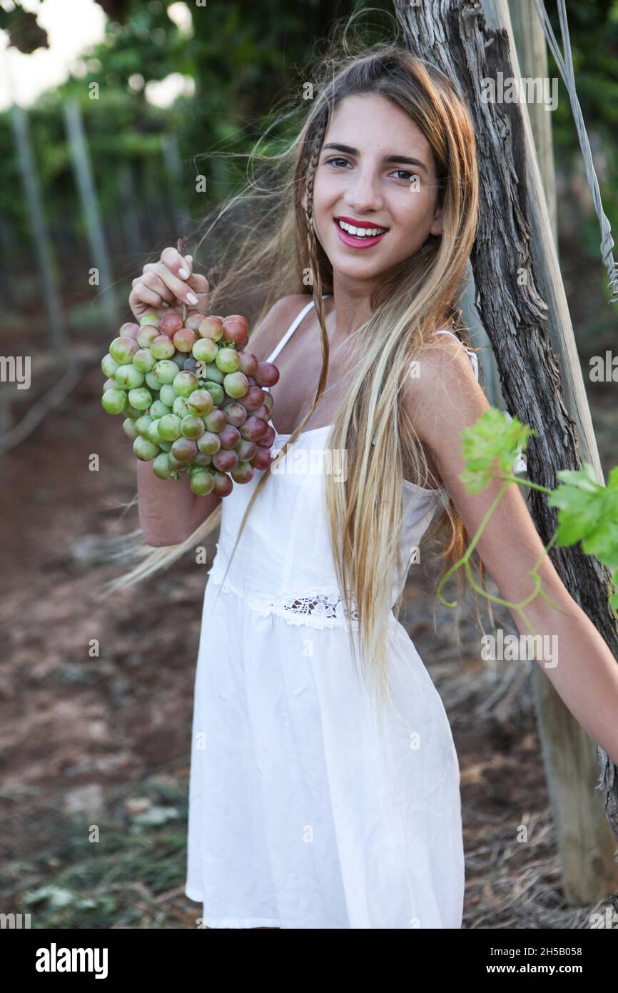 Junge Teen-Mädchen im weißen Kleid nimmt Trauben im Weinberg Stockfoto