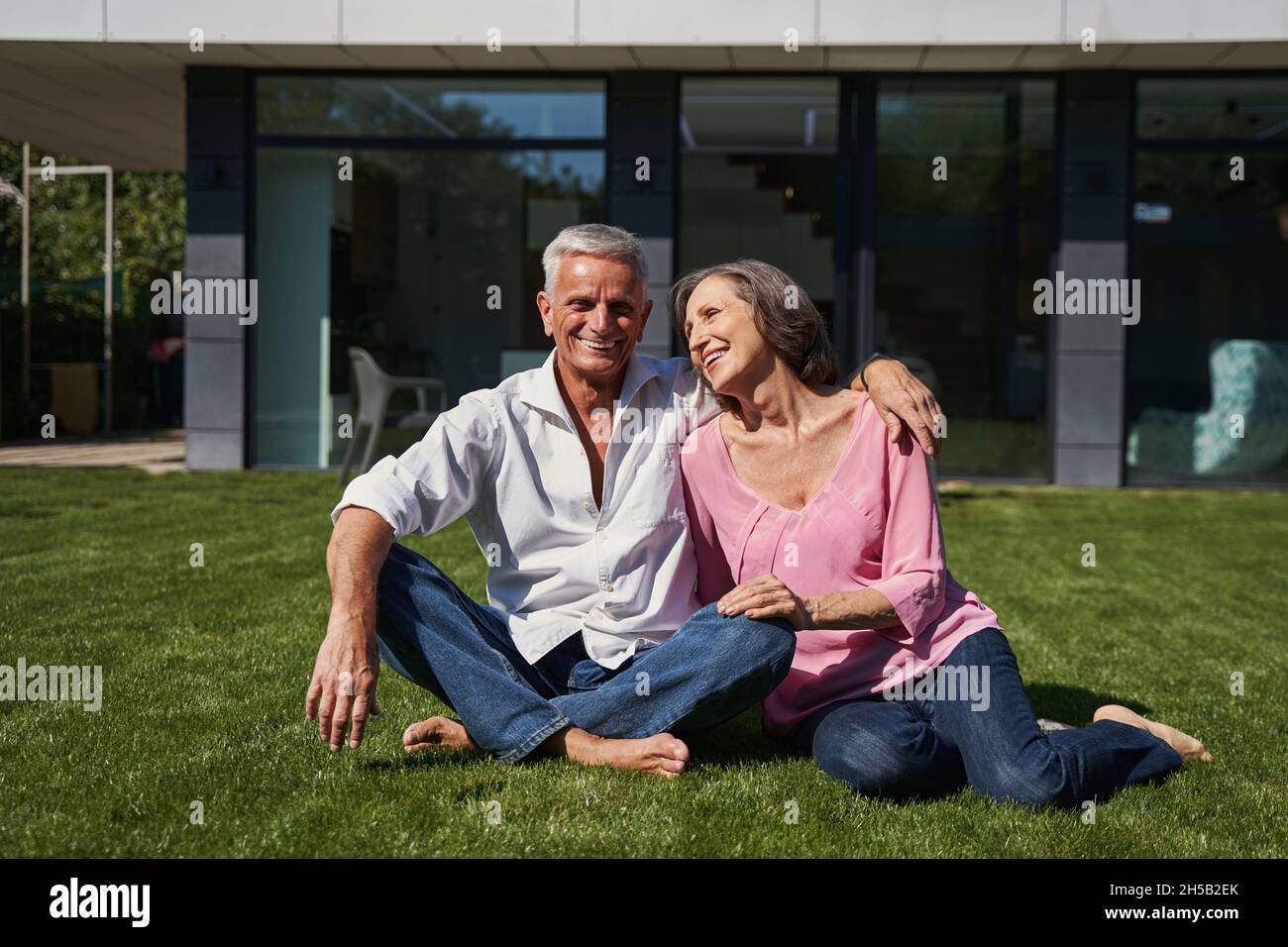 Älterer Mann und alternde Dame sitzen vor dem Haus zusammen Stockfoto