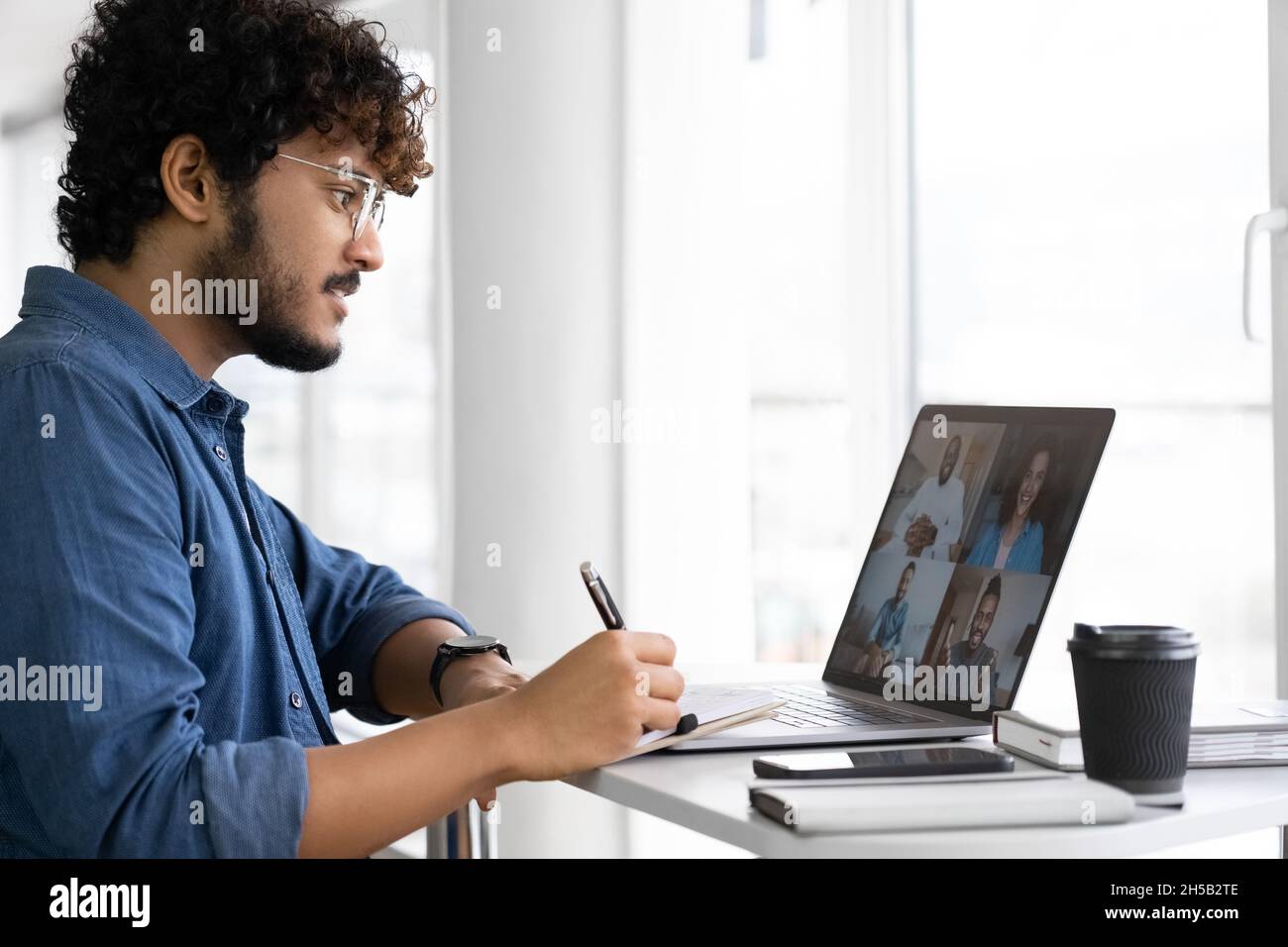 Indischer Mann, der eine App für die Videokommunikation im Fernverkehr mit Kollegen über einen Laptop verwendet Stockfoto