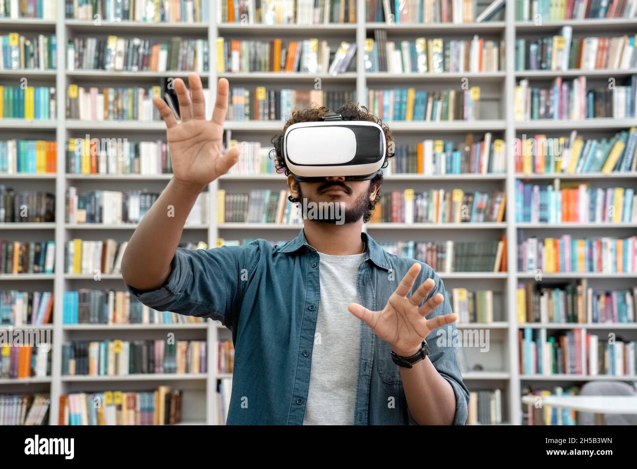 Junge indische Studentin mit VR-Simulator für das Studium in der Universitätsbibliothek Stockfoto