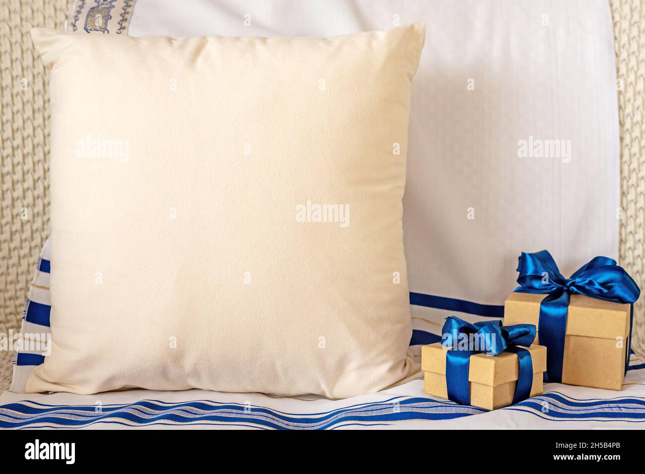 Komposition mit blanko grauen Kissen und Geschenkboxen auf Tallit Stockfoto
