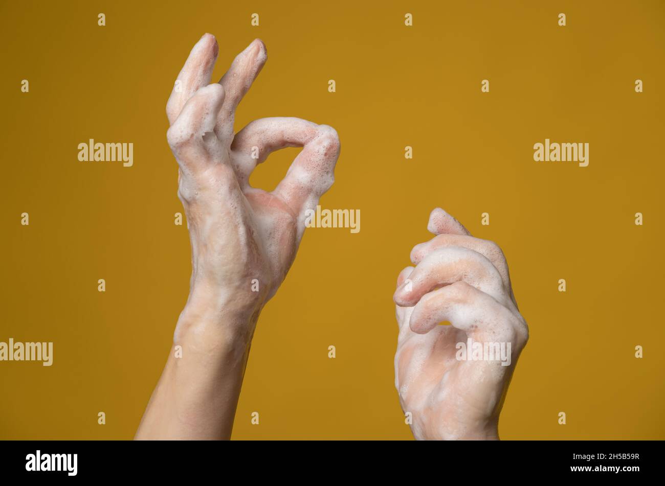 Hände in Seifenschaum, eine von ihnen zeigt mit ihren Fingern ein OK-Zeichen. Konzept für eine effektive Möglichkeit, die Ausbreitung von Infektionen zu verhindern. Stockfoto