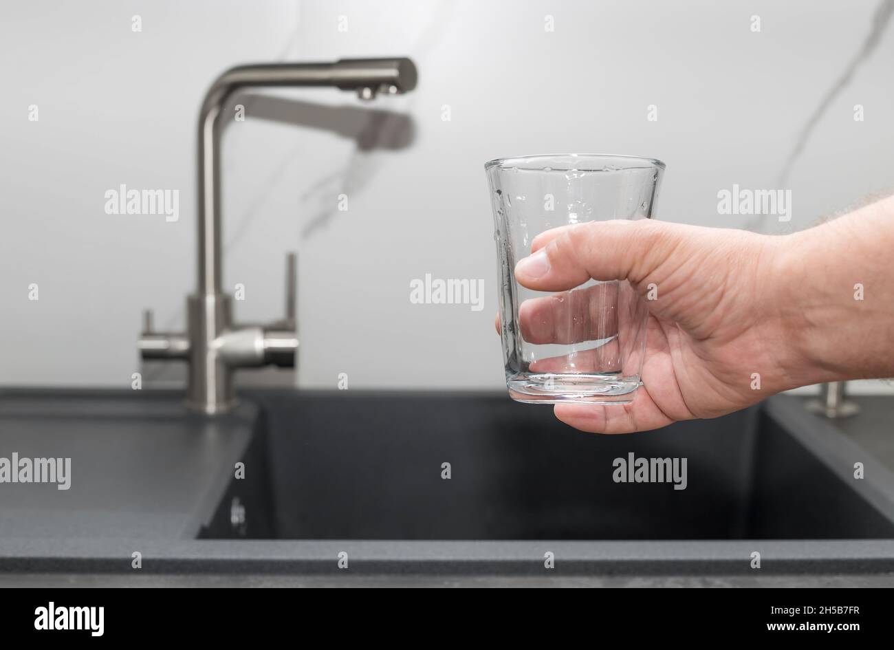 Mann bereit, gefiltertes Wasser in Glas zu gießen Stockfoto