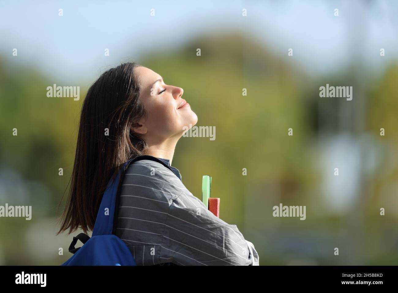 Seitenansicht Porträt eines glücklichen Studenten, der auf einem Campus frische Luft atmet Stockfoto