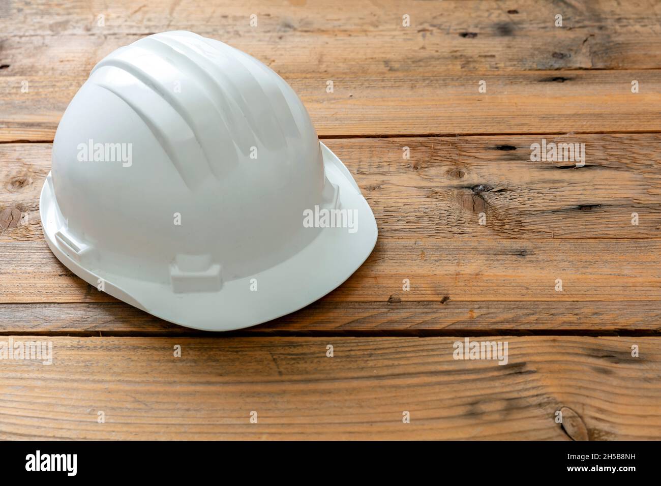 Schutzhelm, weißer Schutzhelm. Baustelleningenieur persönliche Schutzkopfausrüstung, Holzhintergrund Stockfoto