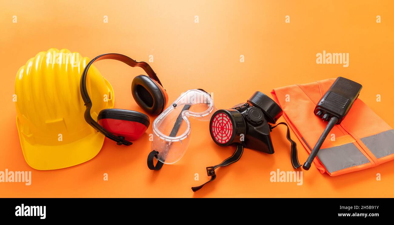 Arbeit Tragen Sie Sicherheitsausrüstung auf orangefarbenem Hintergrund, persönliche Schutzausrüstung. Industriebaustellenarbeiter Gesundheit und Sicherheit Konz Stockfoto