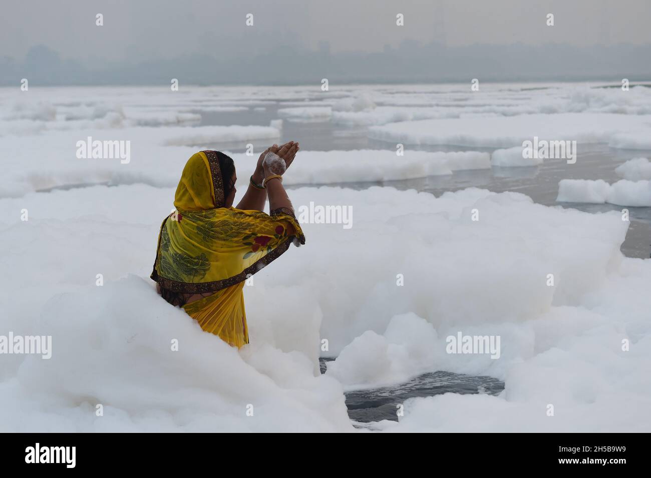 Neu-Delhi, Indien. November 2021. Giftiger Schaum schwimmt auf der Oberfläche des verschmutzten Yamuna-Flusses, während hinduistische Anhänger nach einem Bad im Rahmen der Rituale des viertägigen „Chhath Puja“-Festivals am Montag, dem 8. November 2021, in Neu Delhi, Indien, beten. Das alte hinduistische Fest, das dem sonnengott gewidmet ist, wird für das Wohlergehen, die Entwicklung und den Wohlstand der Familienmitglieder gefeiert. Foto von Abhishek/UPI. Kredit: UPI/Alamy Live Nachrichten Stockfoto