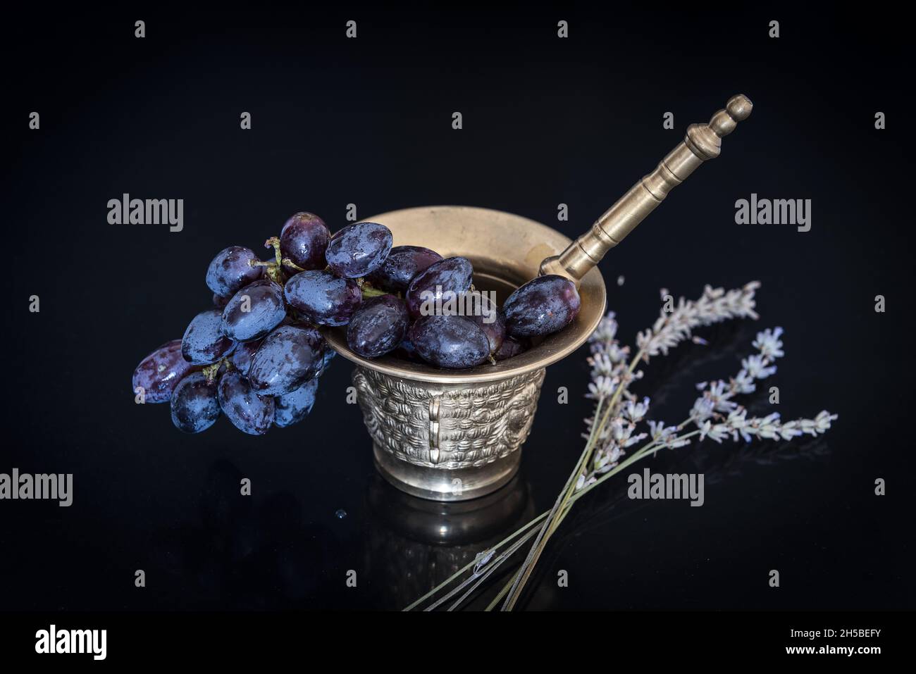 Bronzemörtel mit frisch geernteten natürlichen Trauben. Stockfoto