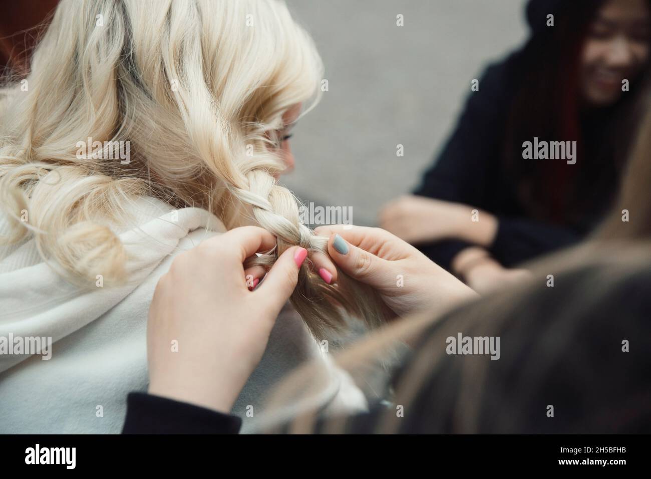 Verkürzte Hände von Mädchen Flechten Haare einer Freundin Stockfoto