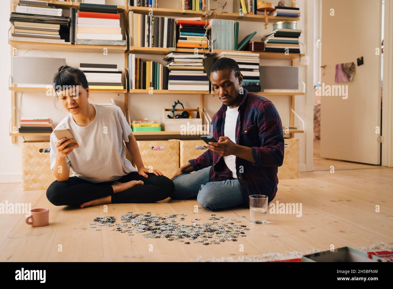 Mittlerer Erwachsener, männlich und junge Frau, die zu Hause ein Smartphone benutzen Stockfoto