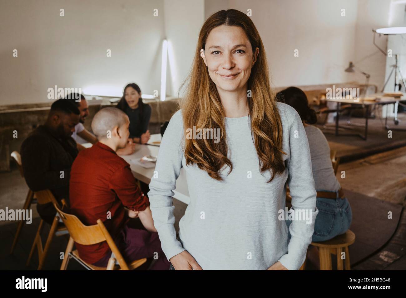 Porträt einer selbstbewussten Geschäftsfrau mit Kollegen im Hintergrund beim Startup-Unternehmen Stockfoto