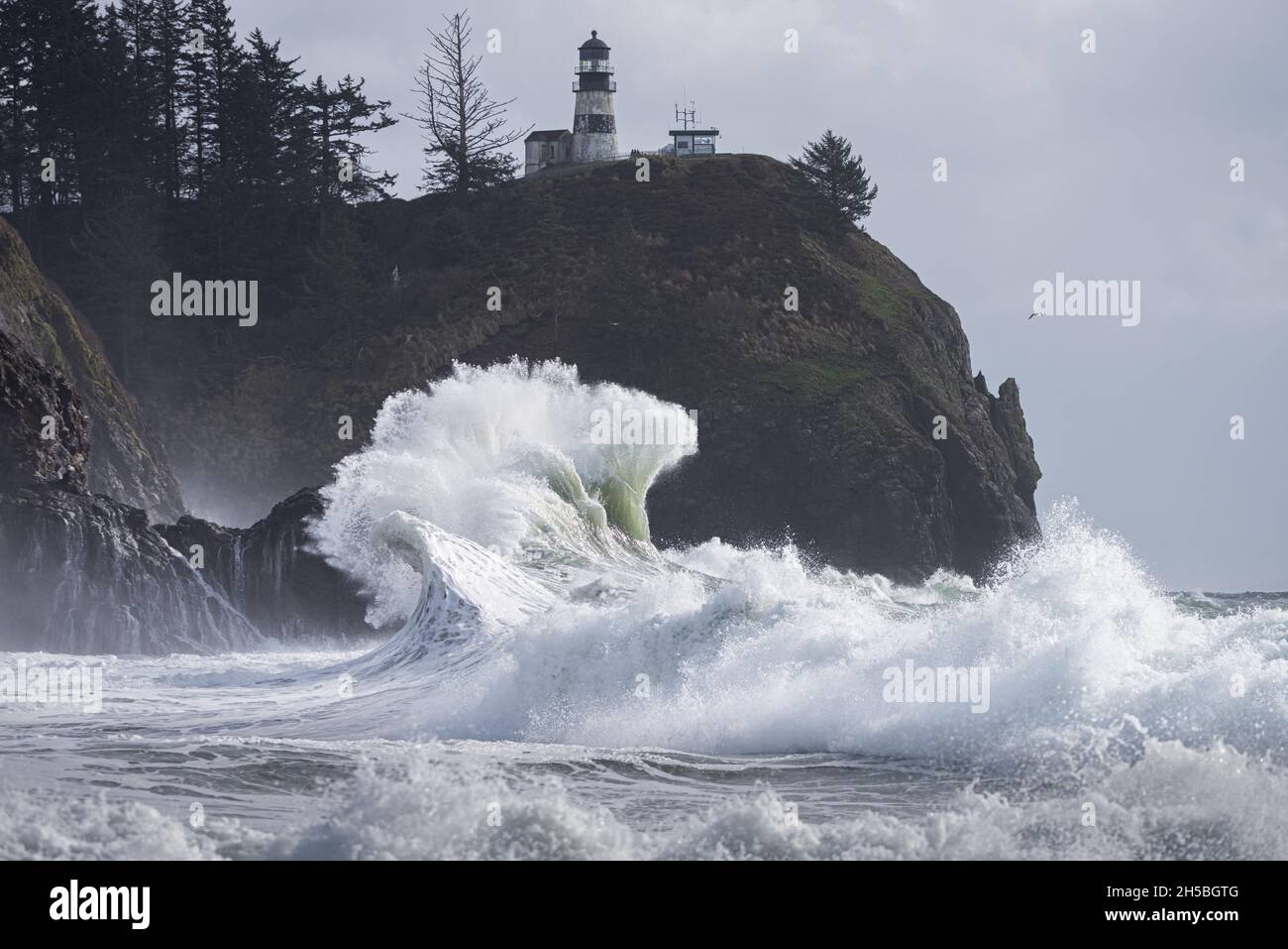 Wunderschöne, kraftvolle, krachende Welle unter der Lichthauslandschaft während des Regensturms an der Washingtoner Küste, Cape Disappointment State Park Stockfoto