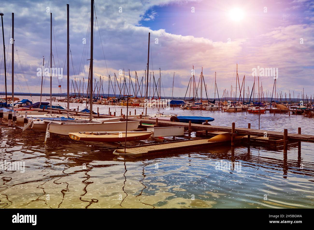 Private kleine Segelboote und Yachten liegen ausgepackt auf dem Pier des Sees in der Sonne Stockfoto