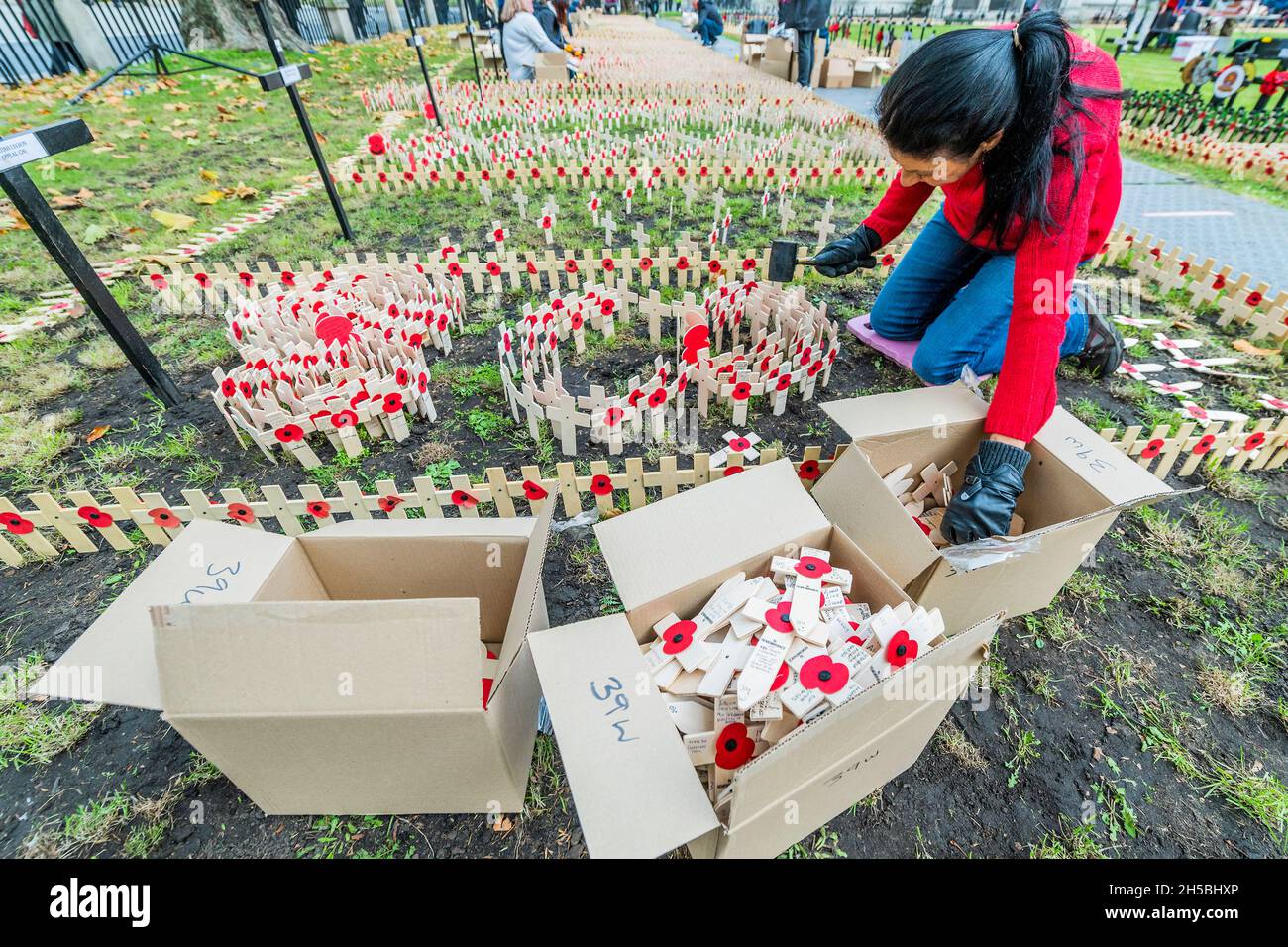 London, Großbritannien. November 2021. Kreuze mit Mohnblumen werden von Freiwilligen (aus der Poppy Factory, der RBL und Unternehmen in london) mit Erinnerungsbotschaften von Einzelpersonen gelegt - das Erinnerungsfeld wird vor der Westminster Abbey vorbereitet. Kredit: Guy Bell/Alamy Live Nachrichten Stockfoto