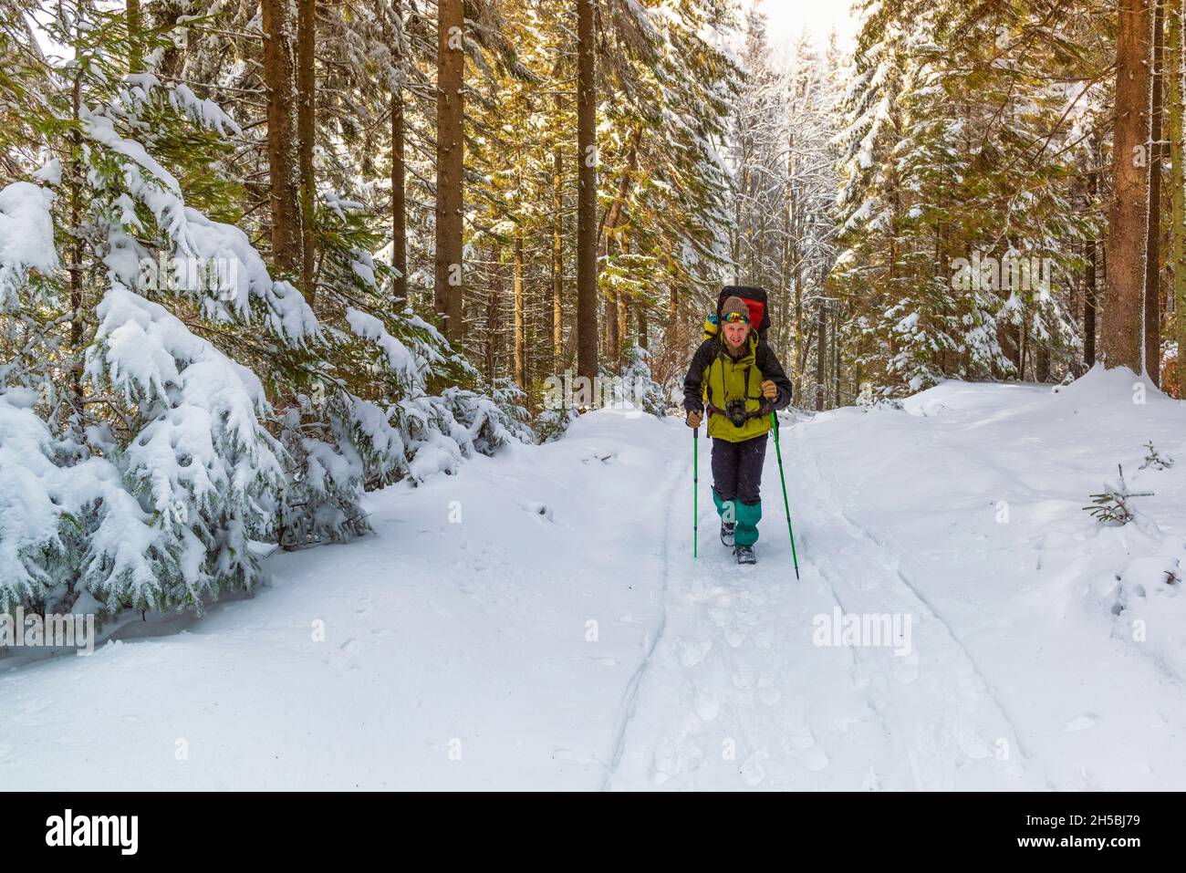 Fröhlicher Winterwanderer mit Rucksack. Outdoor-Aktivitäten im Winter Stockfoto