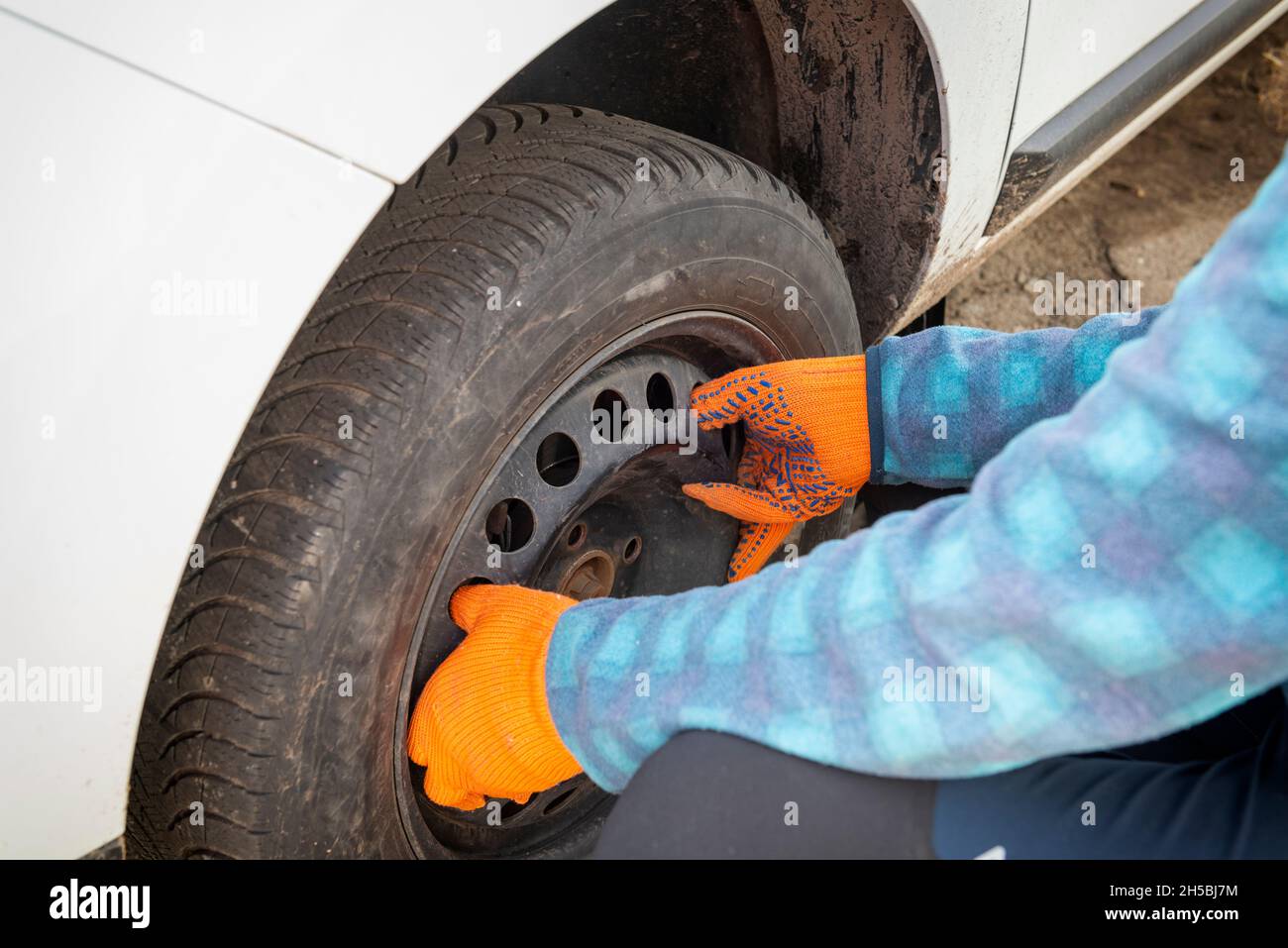 Austausch des beschädigten Platten Reifens. Auto Mechaniker Hände halten schmutzigen Reifen auf dem Auto.Selektive Fokus auf Hände Stockfoto