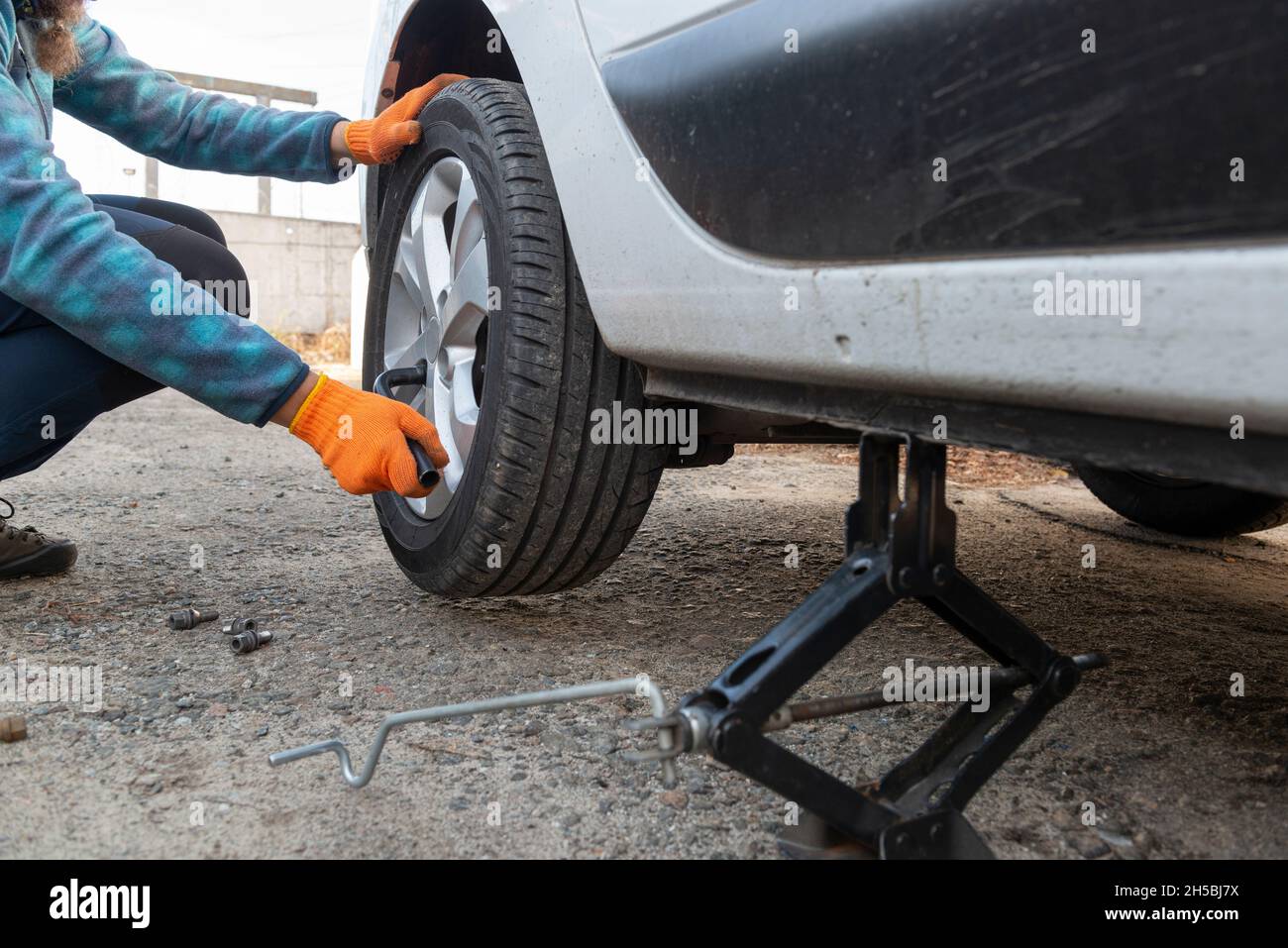 Ersetzen von Reifenpanne. Auto Mechanic ersetzt das Autorad. Auto auf dem Wagenheber. Selektiver Fokus auf die Hände Stockfoto