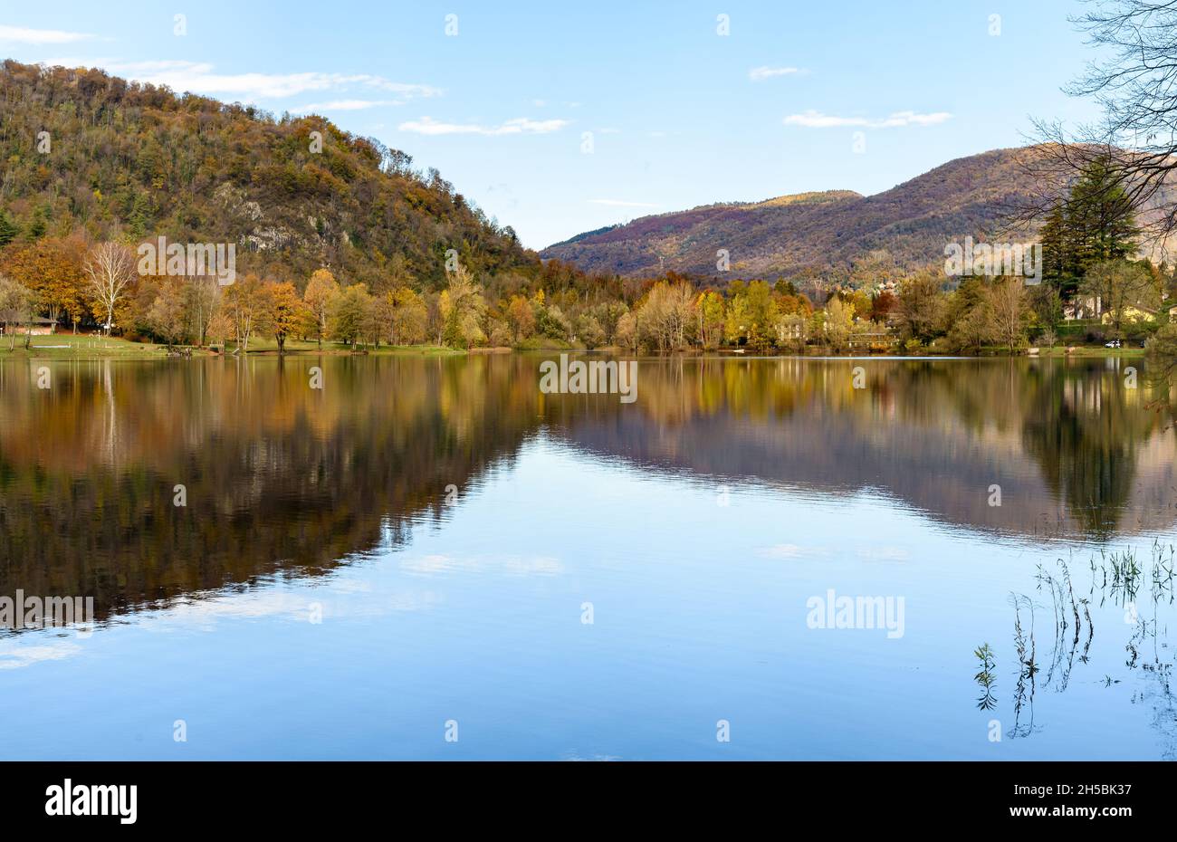 Herbstlandschaft des Ghirla-Sees mit bunten Bäumen und Spiegelungen im Wasser, Valganna, Provinz Varese, Italien Stockfoto