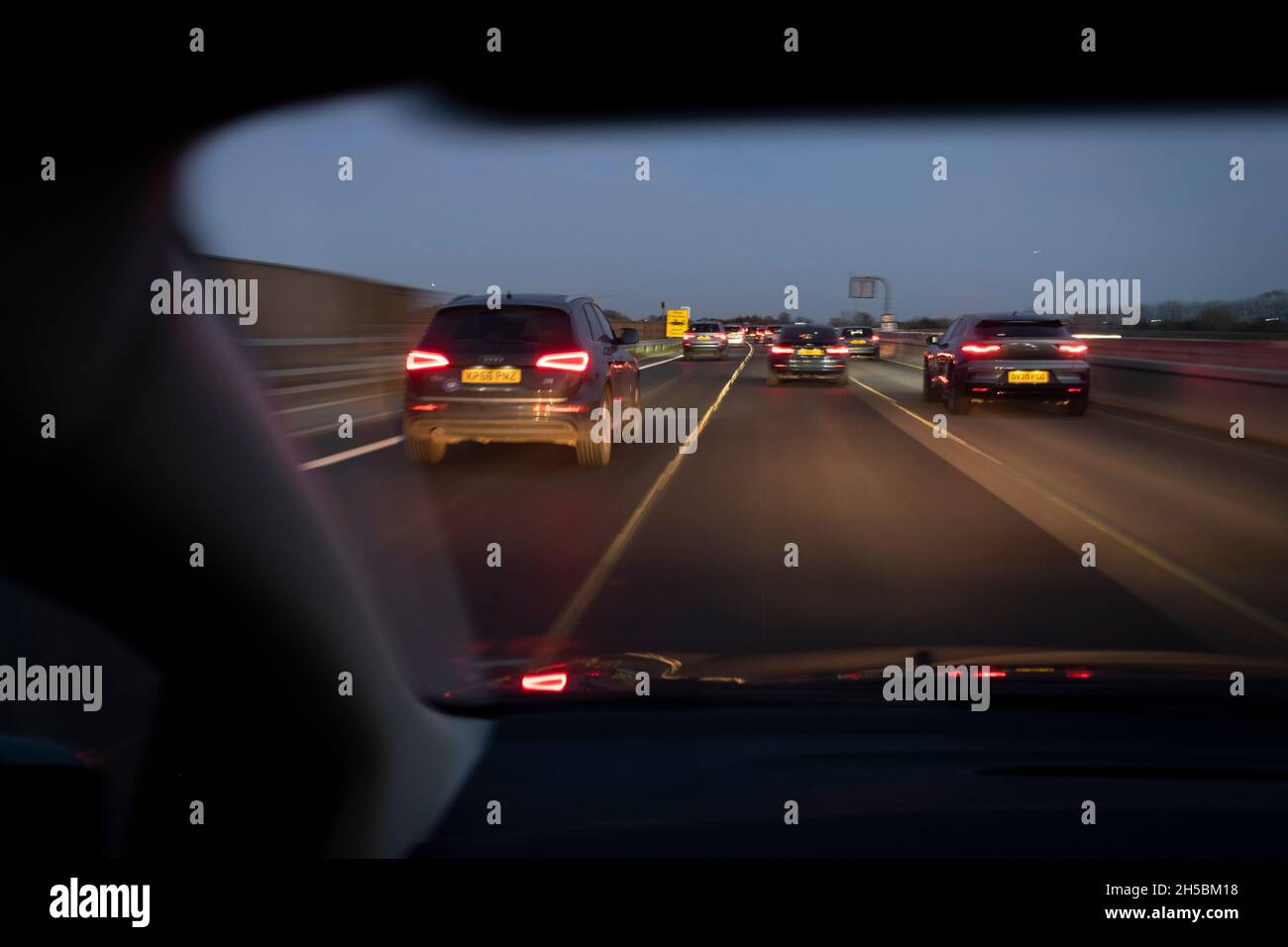 Vom Beifahrersitz eines Autos aus geht am 7. November 2021 in London, England, das Winterlicht durch die Windschutzscheibe in Dunkelheit über, deren Fahrer mit Google Maps auf der Autobahn M4 nach Osten in Richtung London navigiert. Stockfoto