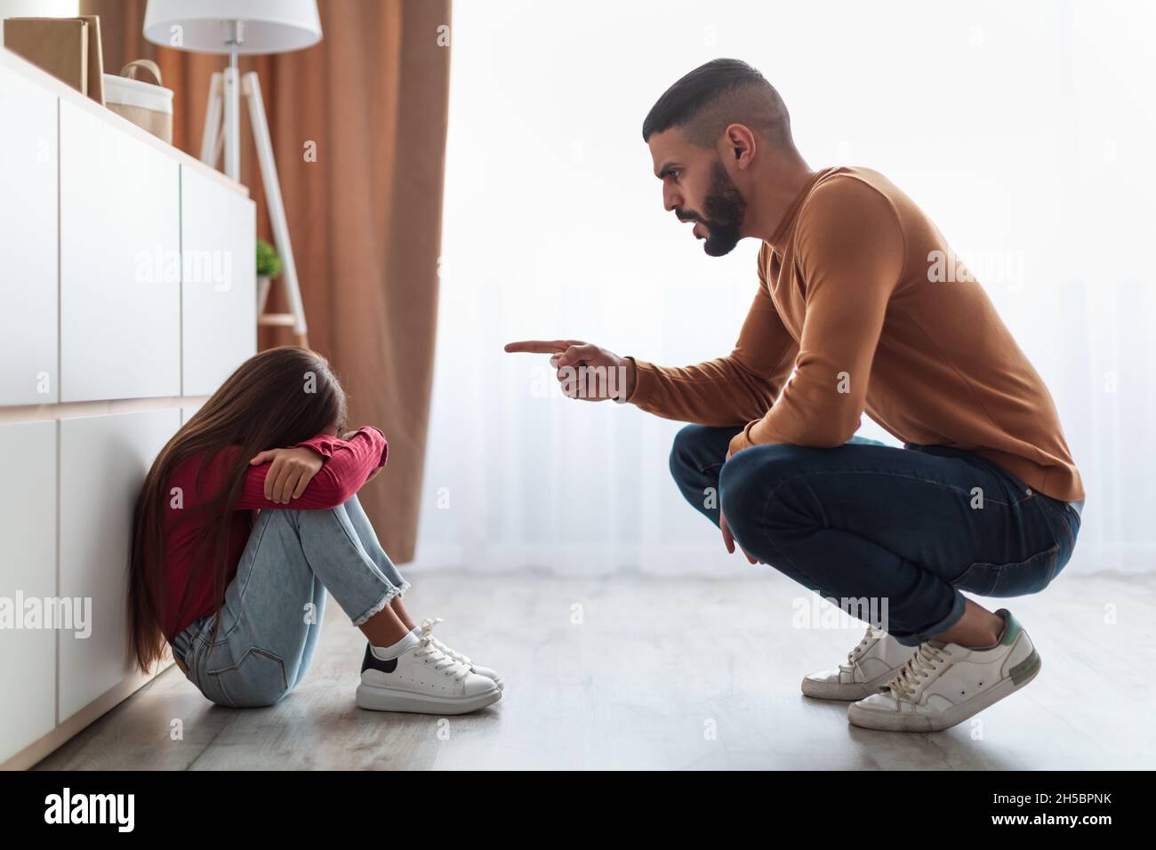 Familienkonflikt. Wütender Vater schimpft traurige Tochter Stockfoto