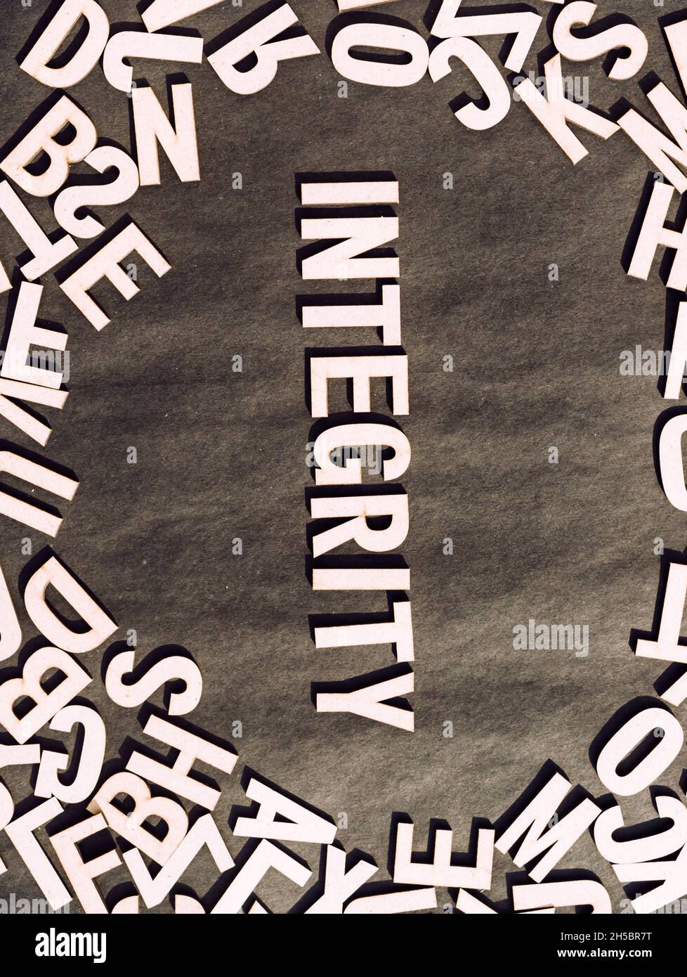 Integrity Word in Holzwürfel Alphabet Letters Draufsicht auf Einem rustikalen Papierhintergrund. Stockfoto