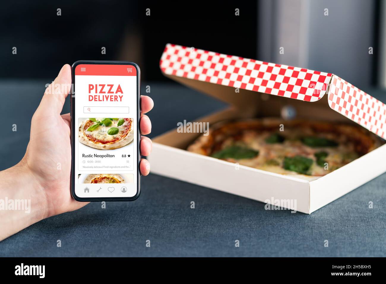 Pizza-Lieferung und Lebensmittel-App am Telefon. Online bestellen Restaurant mitnehmen. Mittagsmenü auf dem Handybildschirm mit Takeout-Box. Hungriger Kunde. Stockfoto