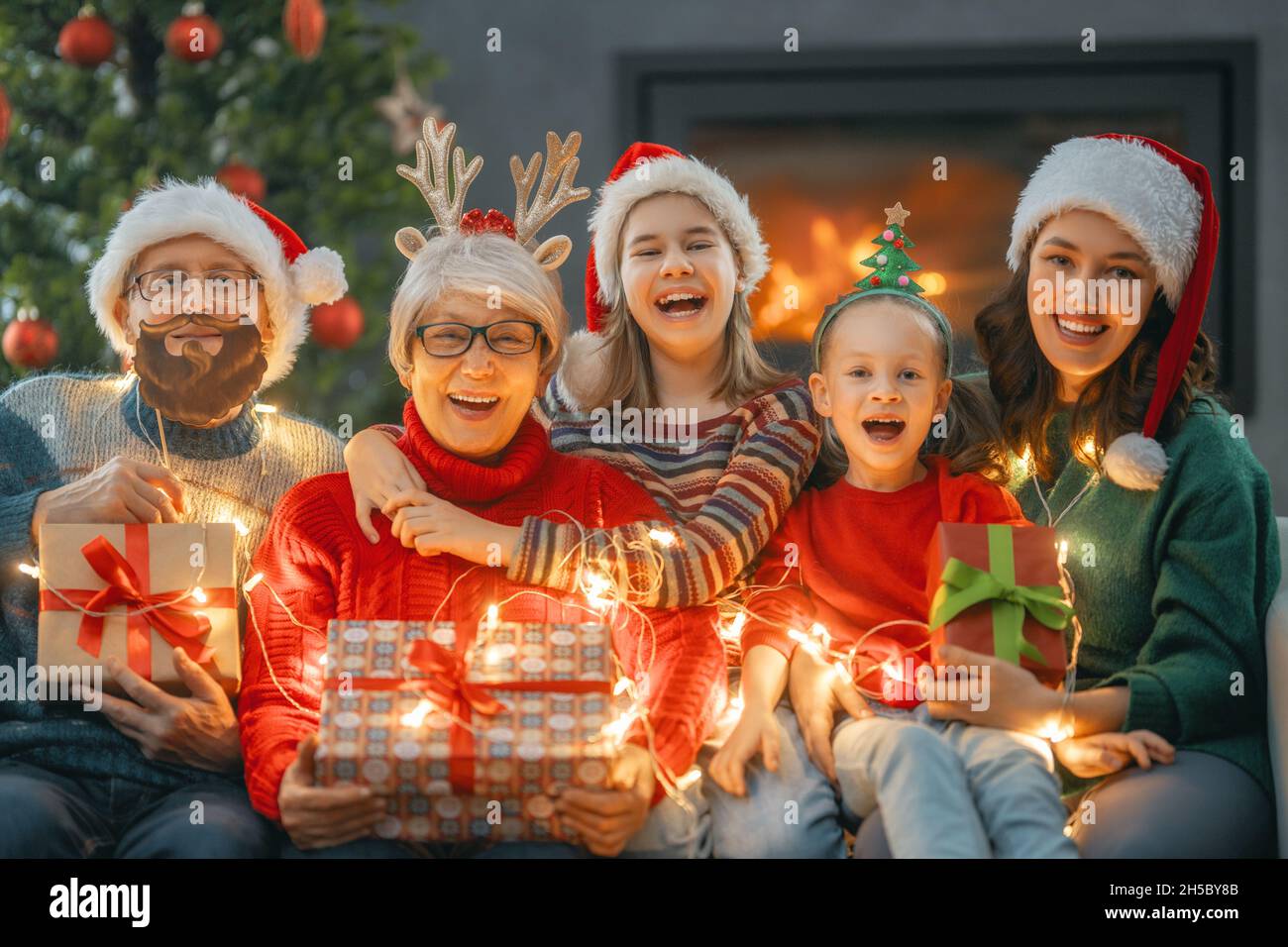 Frohe Weihnachten und frohe Feiertage. Oma, Opa, Mama und Kinder tauschen Geschenke aus. Eltern