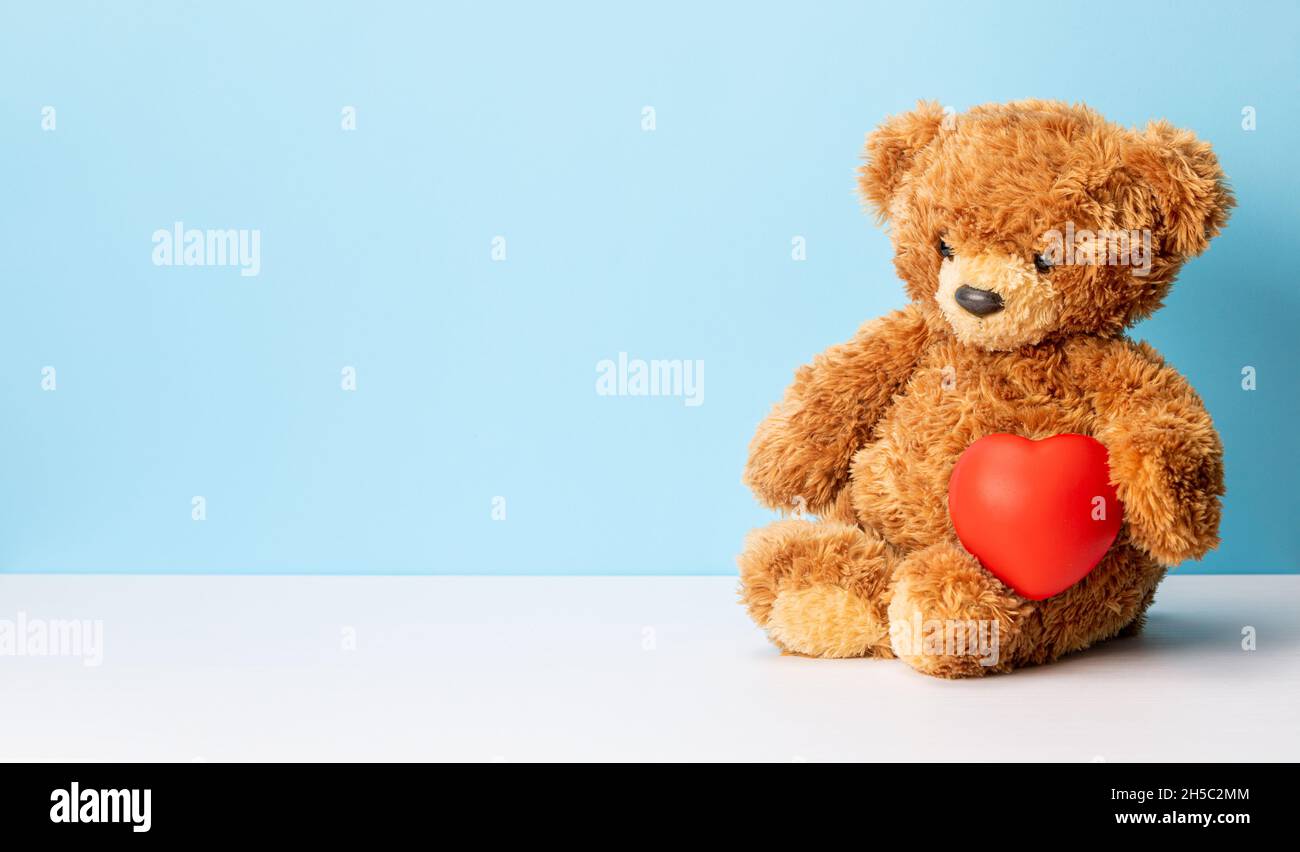 Teddybär hält ein Herz auf einem Hintergrund. Valentinstag. Stockfoto