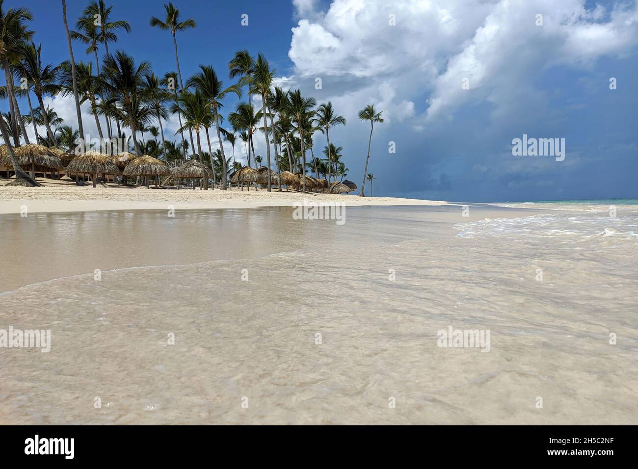 Paradiesischer tropischer Strand und Ozean, Blick auf weißen Sand, Kokospalmen über Sonnenschirmen und Liegestühlen. Badeort, Urlaub auf malerischer Insel Stockfoto